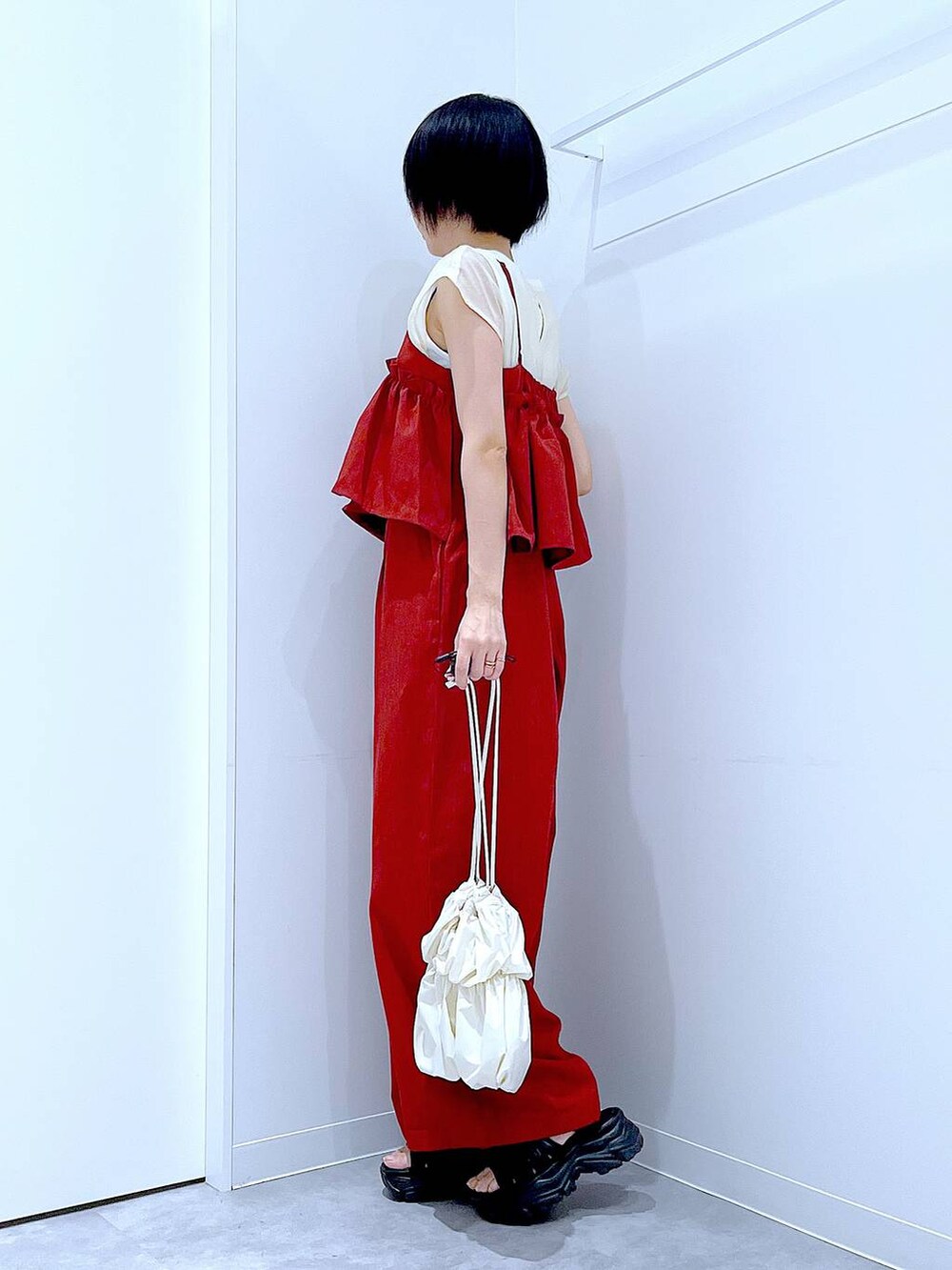 ブラック系のスニーカー、ホワイト系のショルダーバッグ、レッド系のつなぎ/オールインワンを着用したレディースの夏コーディネートの3枚目の写真