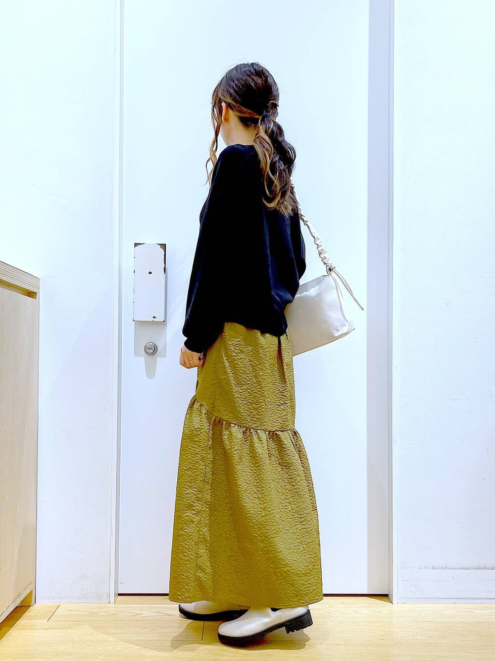 ホワイト系のショルダーバッグ、ベージュ系のブーツ、ブラック系のニット/セーターを着用したレディースの冬コーディネートの4枚目の写真