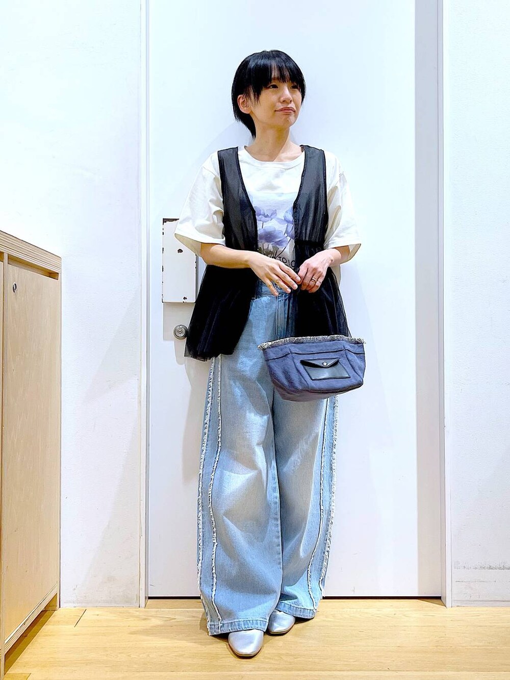 シルバー系のパンプス、ブルー系のショルダーバッグ、ブルー系のデニムパンツを着用したレディースの春コーディネートの2枚目の写真