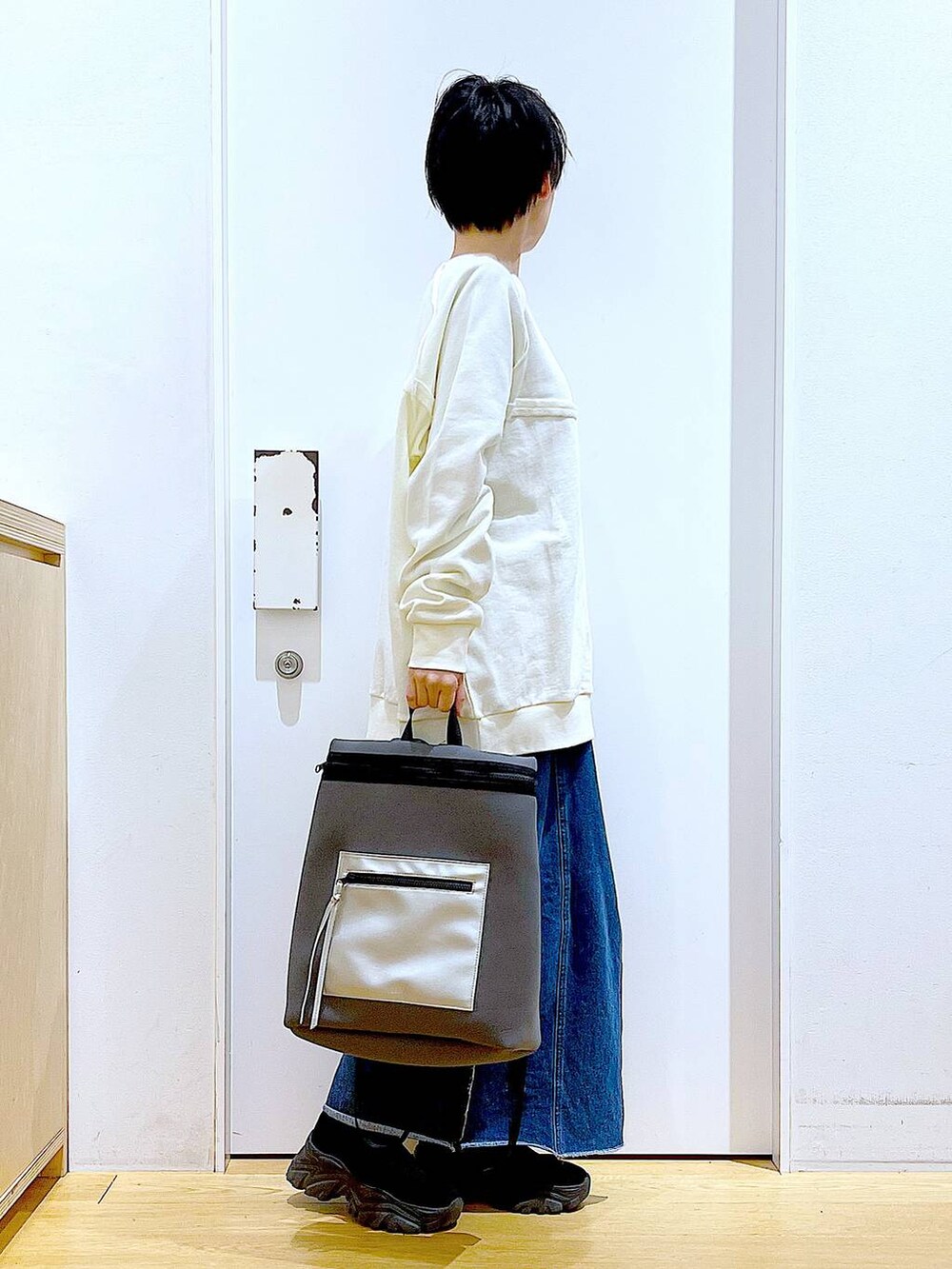 ブルー系のデニムスカート、グレー系のバックパック/リュック、ブラック系のブーツを着用したレディースの冬コーディネートの4枚目の写真