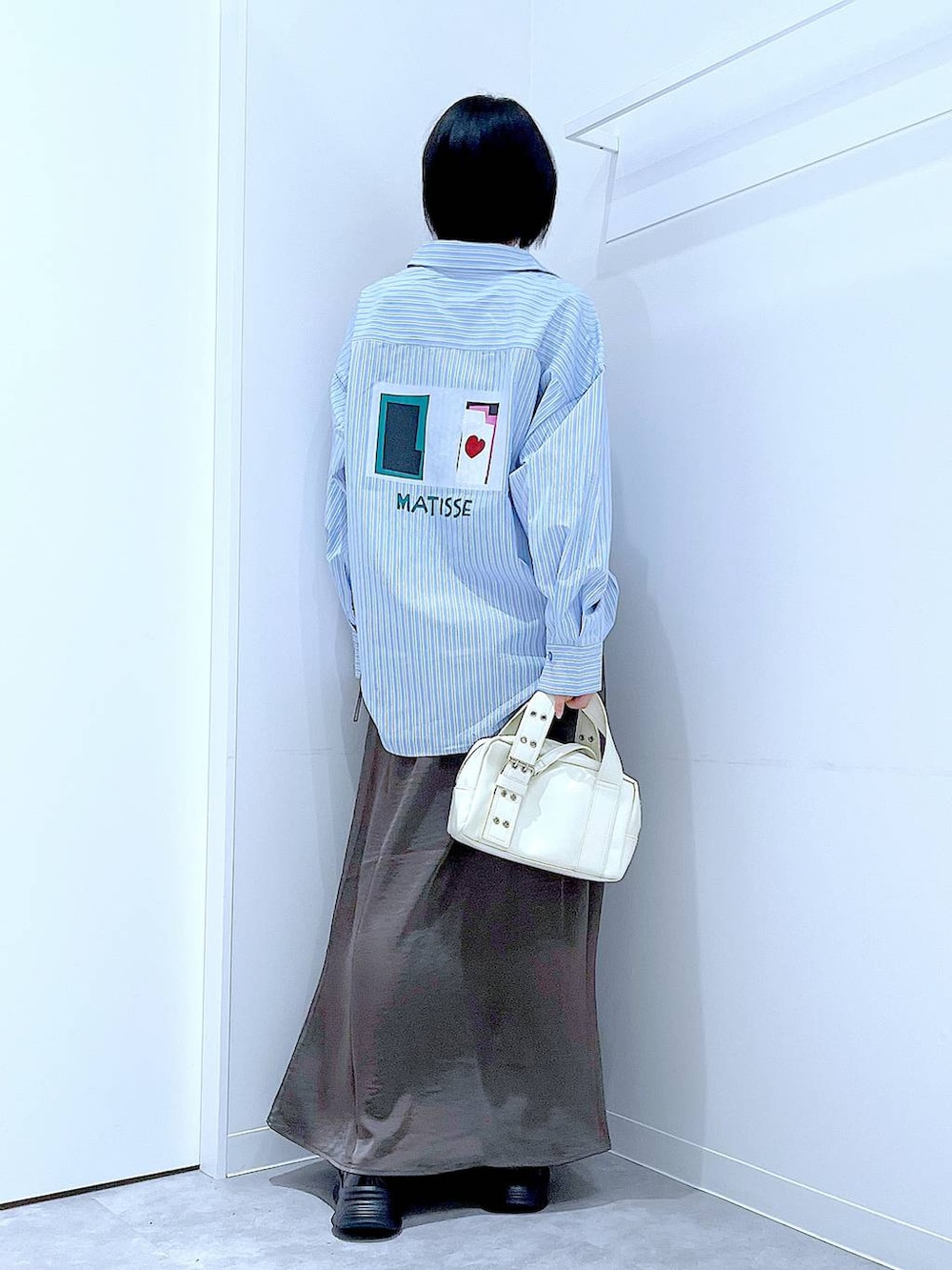 ブラック系のローファー、ホワイト系のショルダーバッグ、グレー系のスカートを着用したレディースの秋コーディネートの5枚目の写真