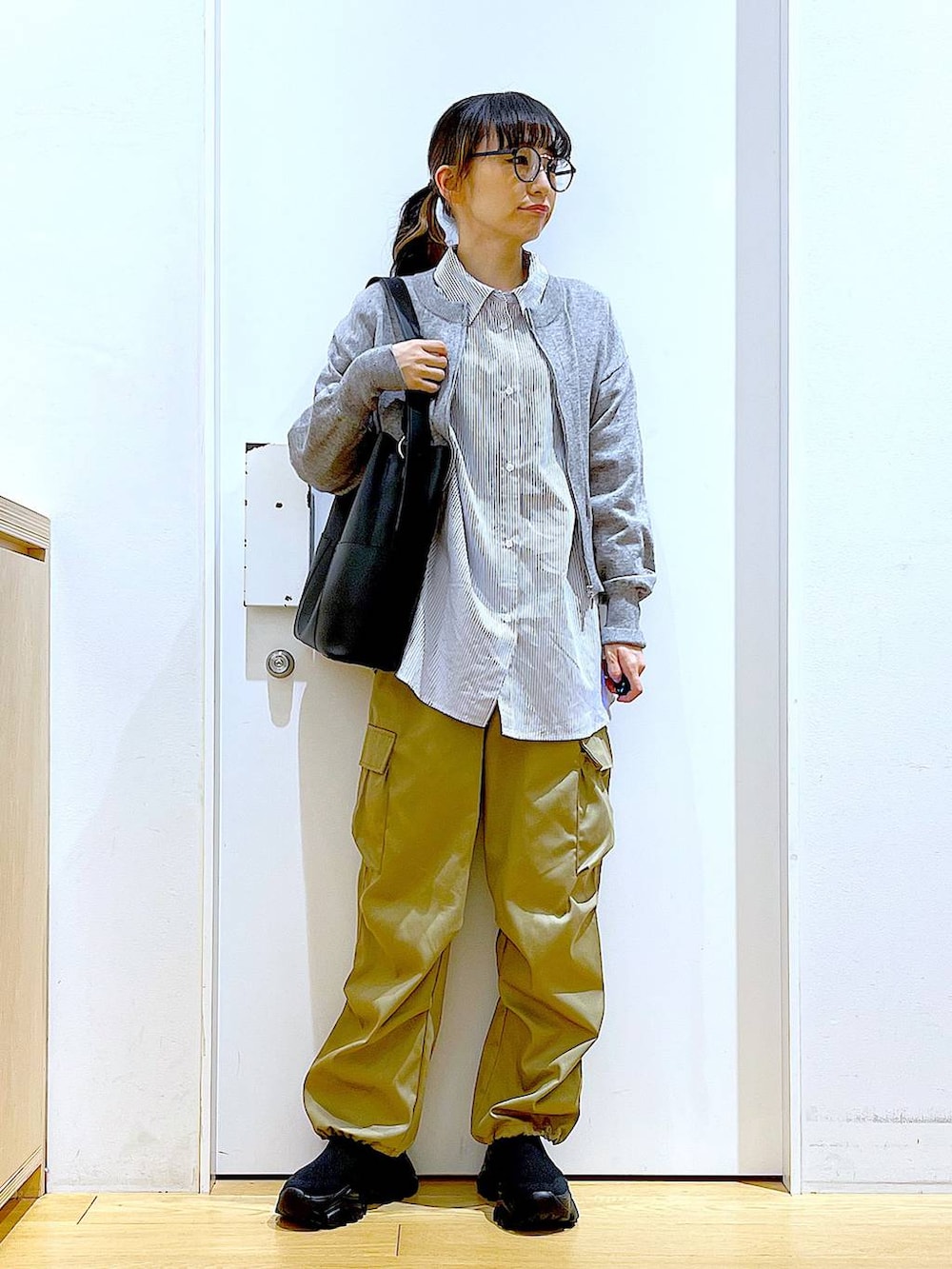 ブラック系のショルダーバッグ、グレー系のカーディガン/ボレロ、ブラック系のスニーカーを着用したレディースの春コーディネートの2枚目の写真