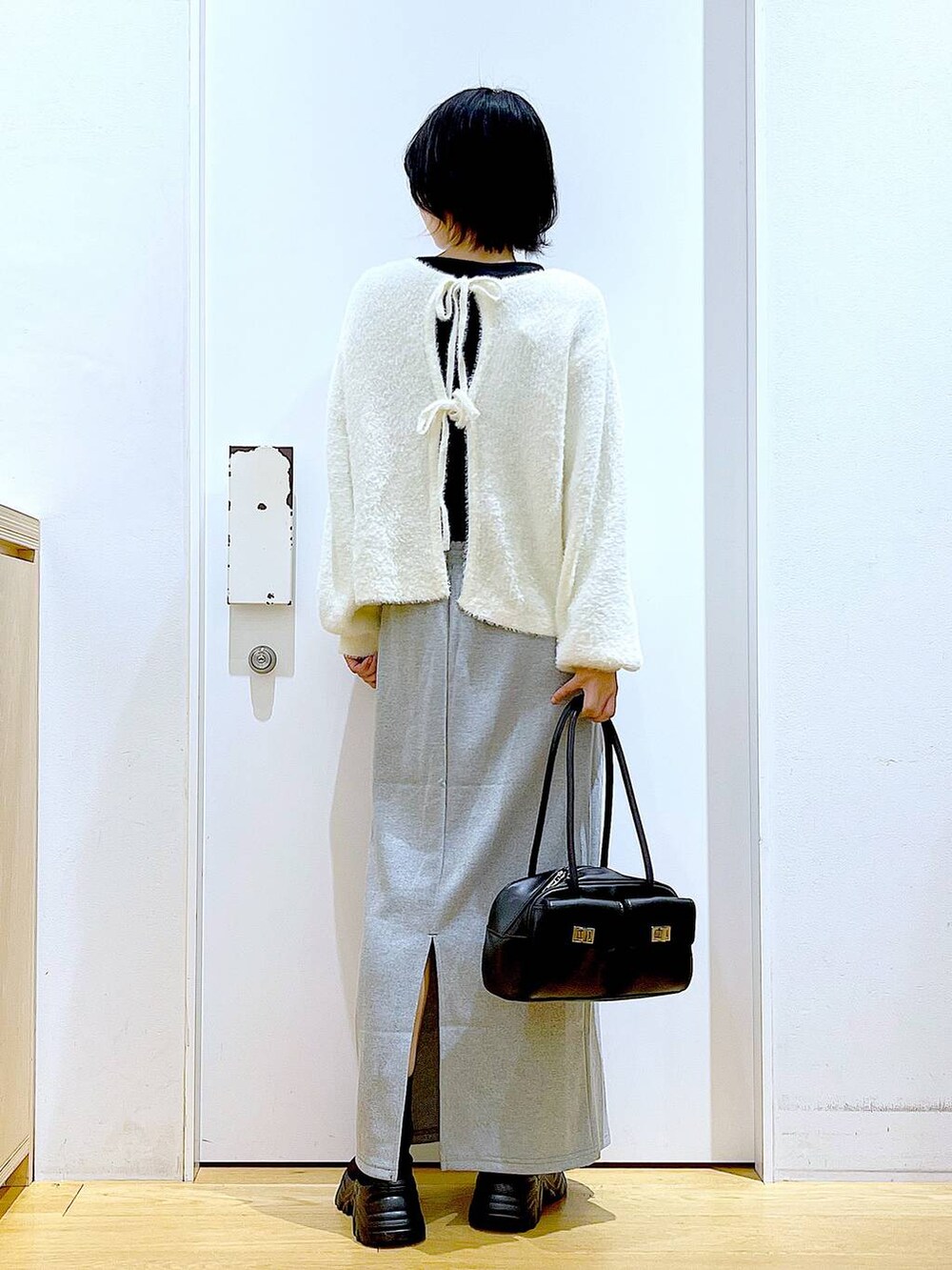 ブラック系のハンドバッグ、ブラック系のブーツ、グレー系のスカートを着用したレディースの冬コーディネートの5枚目の写真