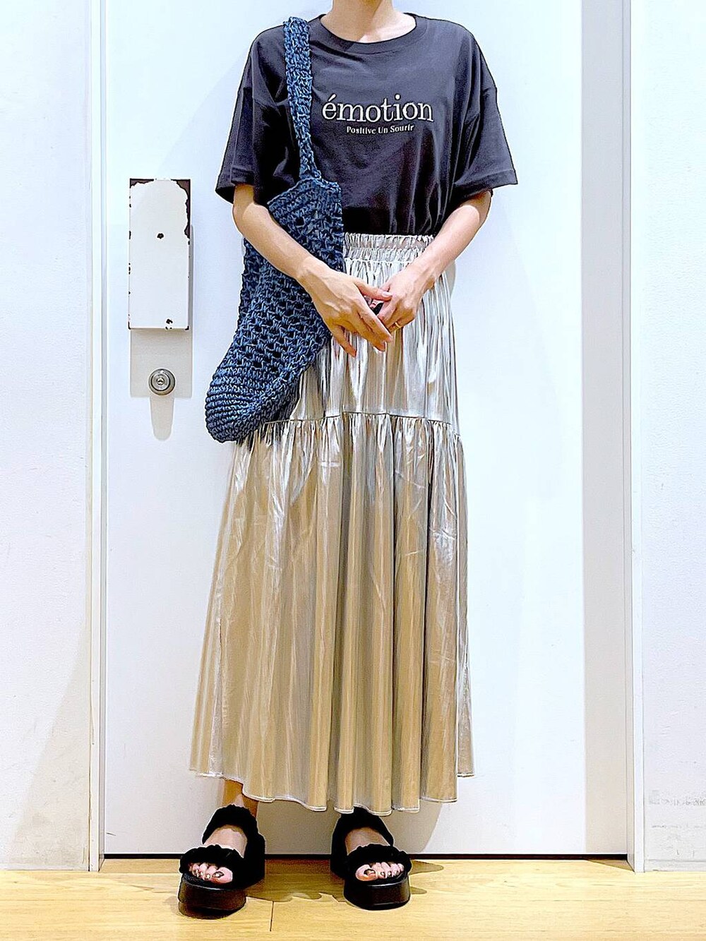 ブラック系のサンダル、シルバー系のスカート、ブルー系のトートバッグを着用したレディースの夏コーディネートの6枚目の写真