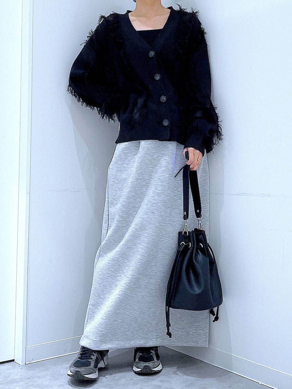 グレー系のスカート、ブラック系のショルダーバッグ、ブラック系のカーディガン/ボレロを着用したレディースの春コーディネートの6枚目の写真