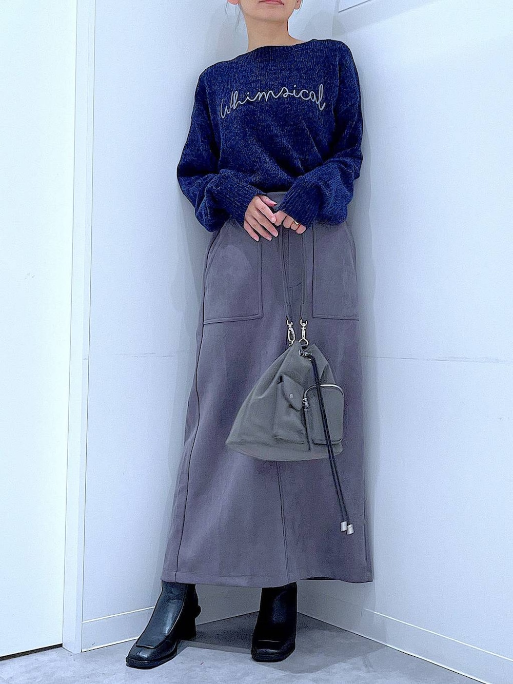 ブラック系のブーツ、ブルー系のニット/セーター、グレー系のスカートを着用したレディースの冬コーディネートの6枚目の写真