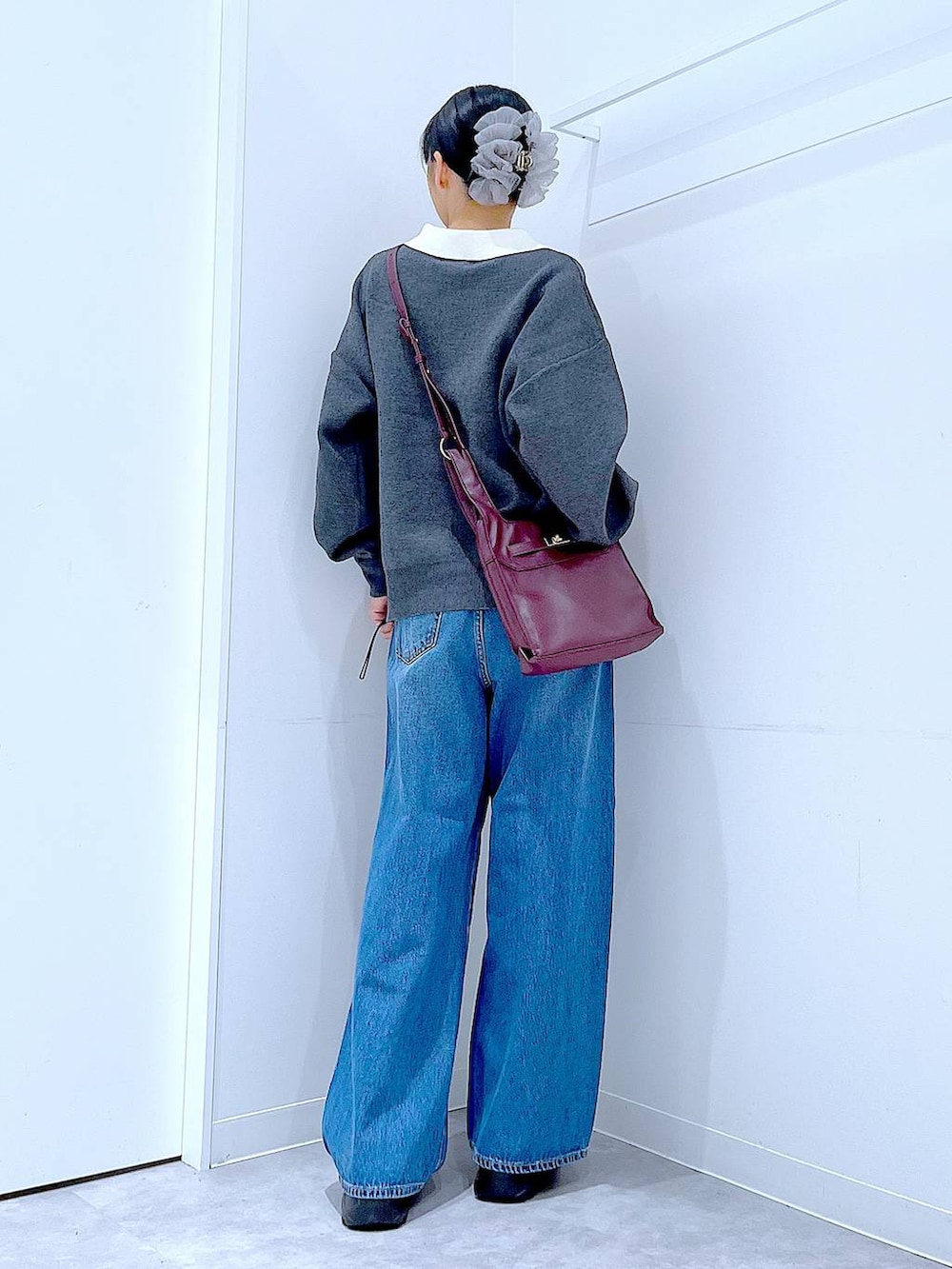 ブルー系のデニムパンツ、レッド系のショルダーバッグ、グレー系のニット/セーターを着用したレディースの秋コーディネートの5枚目の写真