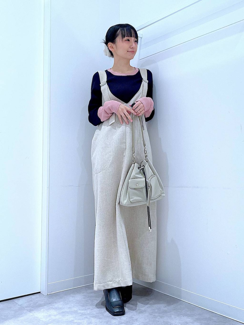 ブラック系のブーツ、ベージュ系のジャンパースカート、ブルー系のニット/セーターを着用したレディースの冬コーディネートの2枚目の写真