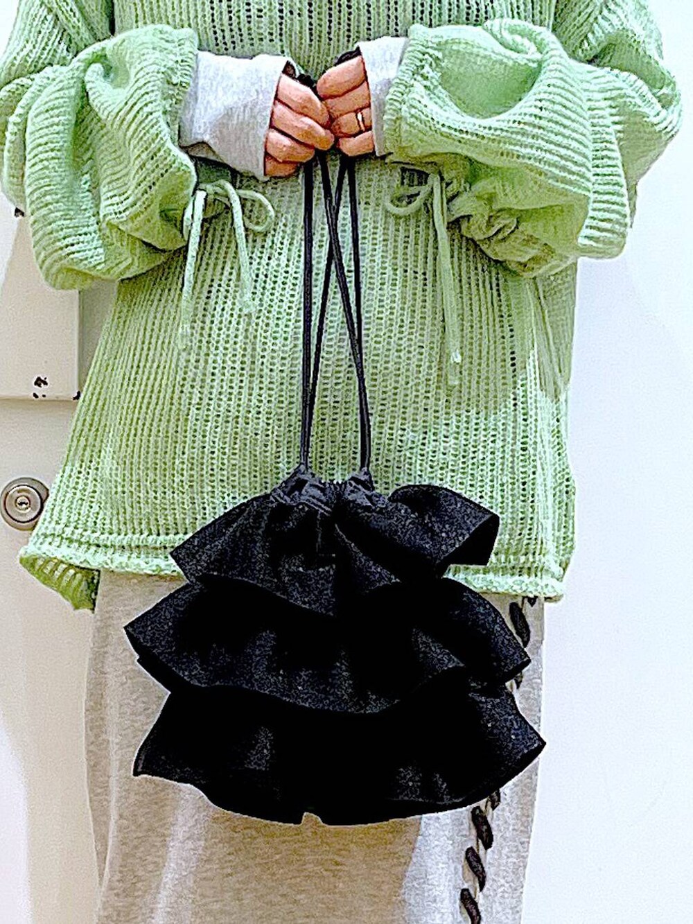 ブラック系のブーツ、グリーン系のニット/セーター、グレー系のスカートを着用したレディースの冬コーディネートの9枚目の写真