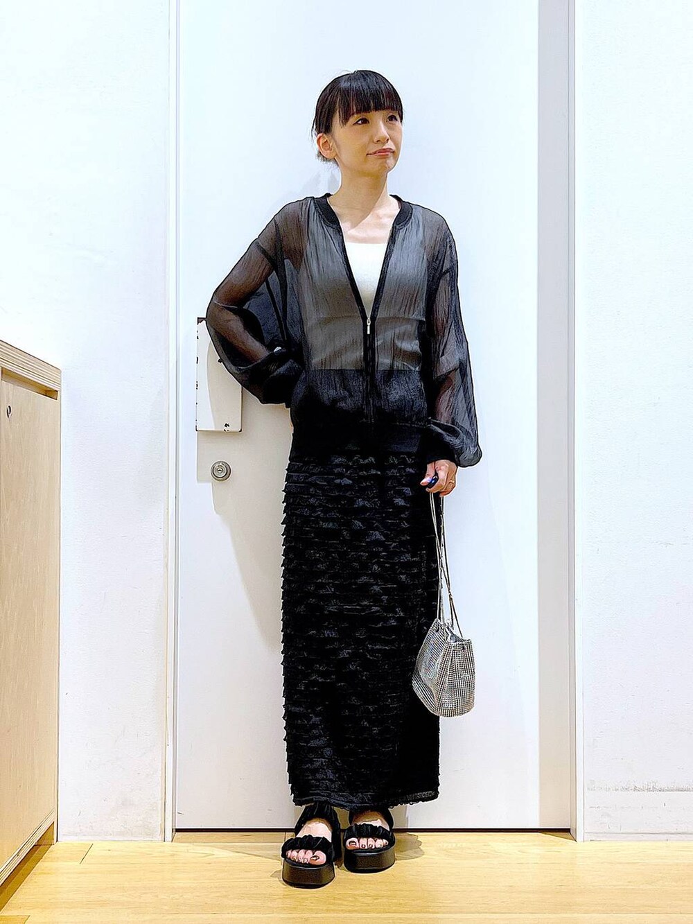 ブラック系のサンダル、ブラック系のブルゾン、ホワイト系のニット/セーターを着用したレディースの夏コーディネートの2枚目の写真