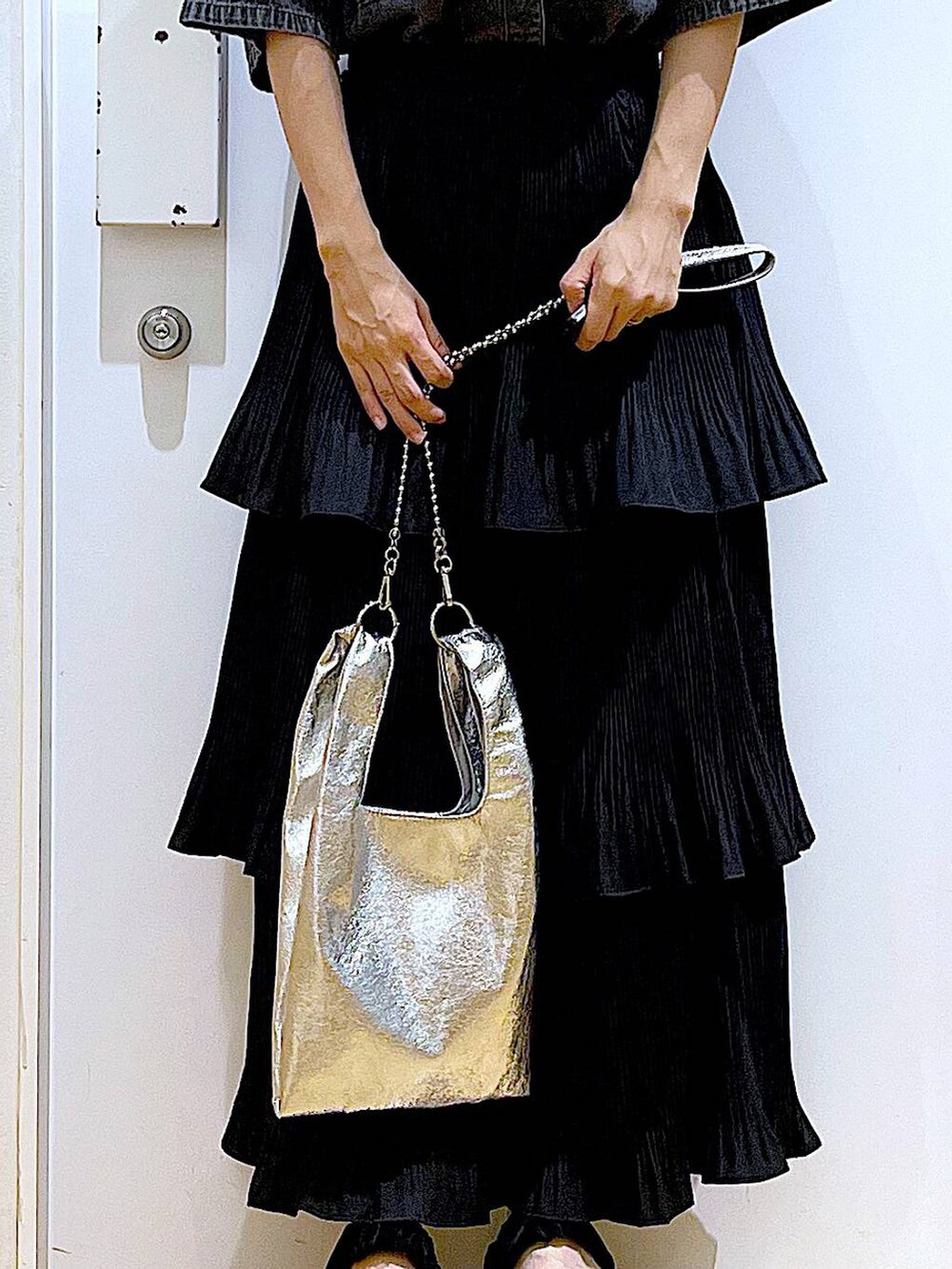 シルバー系のショルダーバッグ、ブラック系のスカート、ブラック系のサンダルを着用したレディースの夏コーディネートの9枚目の写真