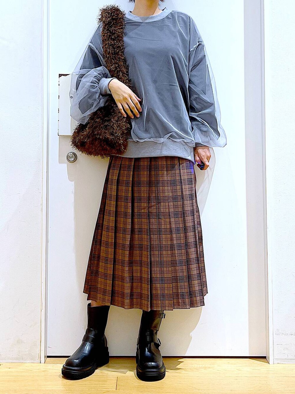 ブラック系のブーツ、ブラウン系のショルダーバッグ、ブラウン系のスカートを着用したレディースの秋コーディネートの6枚目の写真