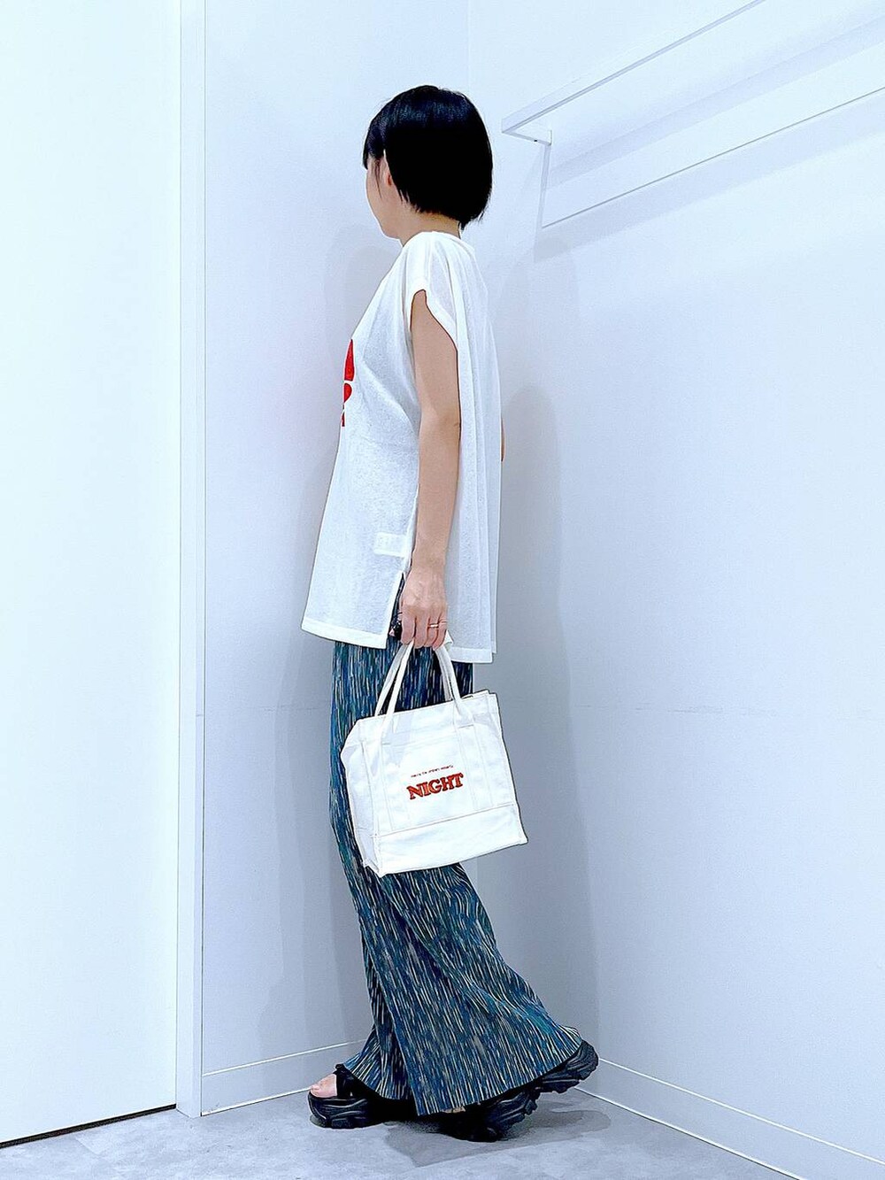 ブラック系のスニーカー、ホワイト系のTシャツ/カットソー、ホワイト系のトートバッグを着用したレディースの夏コーディネートの3枚目の写真