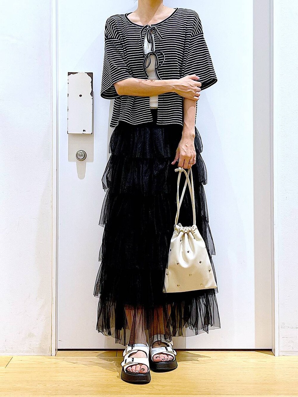 ホワイト系のサンダル、ホワイト系のショルダーバッグ、ブラック系のスカートを着用したレディースの夏コーディネートの6枚目の写真