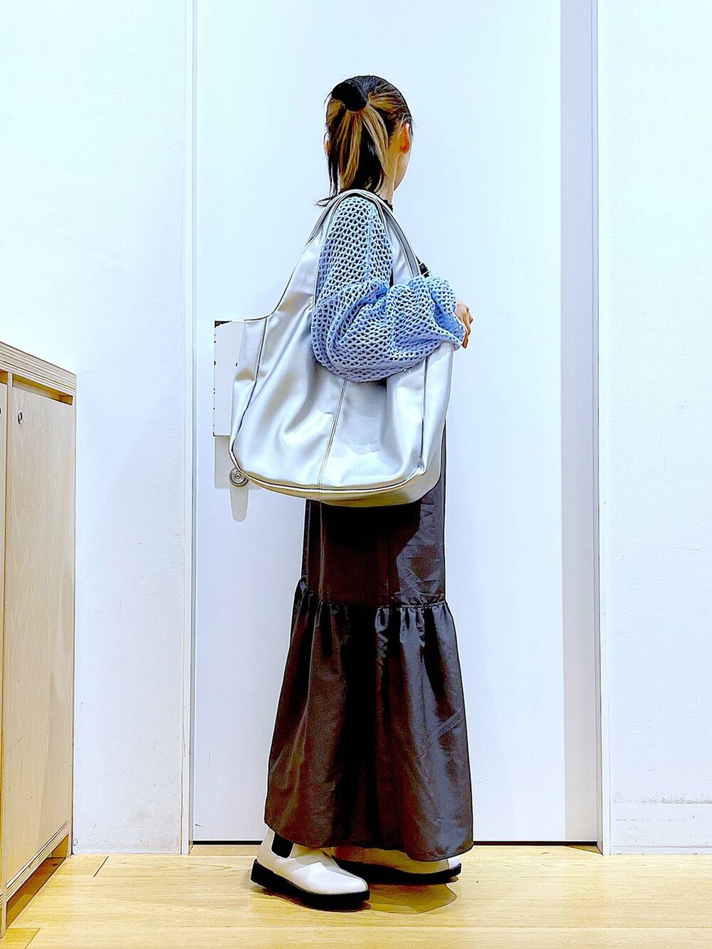 ブラック系のTシャツ/カットソー、ブルー系のニット/セーター、シルバー系のトートバッグを着用したレディースの春コーディネートの4枚目の写真