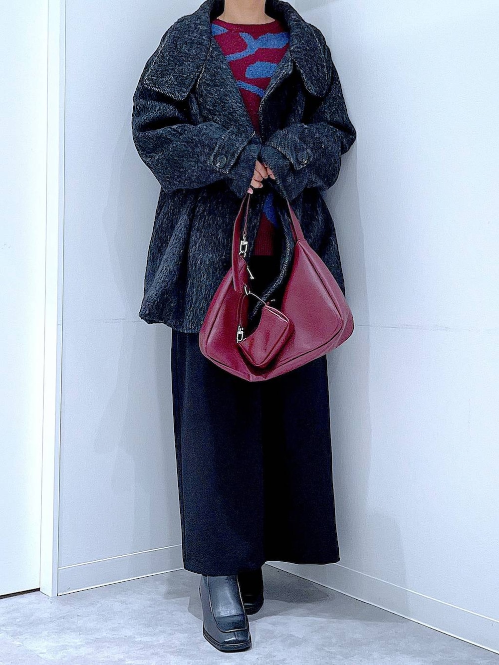 ブラック系のスカート、ブラック系のステンカラーコート、ブラック系のブーツを着用したレディースの冬コーディネートの6枚目の写真