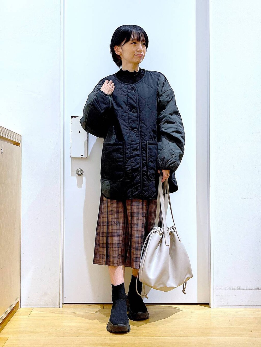 ベージュ系のトートバッグ、ブラック系のブルゾン、ブラック系のTシャツ/カットソーを着用したレディースの秋コーディネートの2枚目の写真