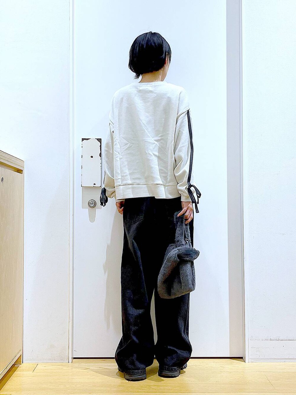 グレー系のショルダーバッグ、ブラック系のブーツ、ベージュ系のスウェットを着用したレディースの秋コーディネートの5枚目の写真