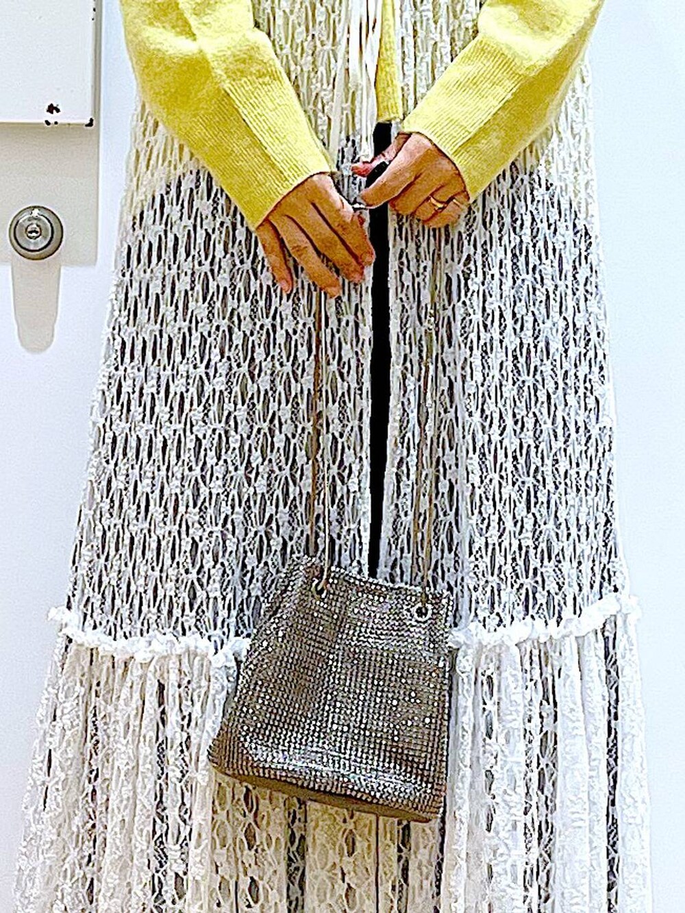 イエロー系のニット/セーター、グレー系のショルダーバッグ、ホワイト系のワンピースを着用したレディースの冬コーディネートの9枚目の写真