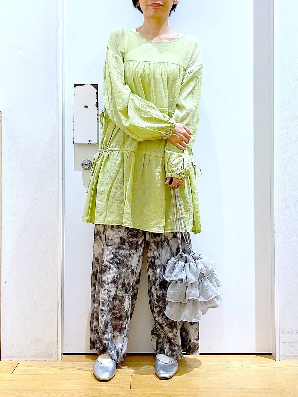 シルバー系のショルダーバッグ、シルバー系のパンプス、グリーン系のチュニックを着用したレディースの春コーディネートの6枚目の写真