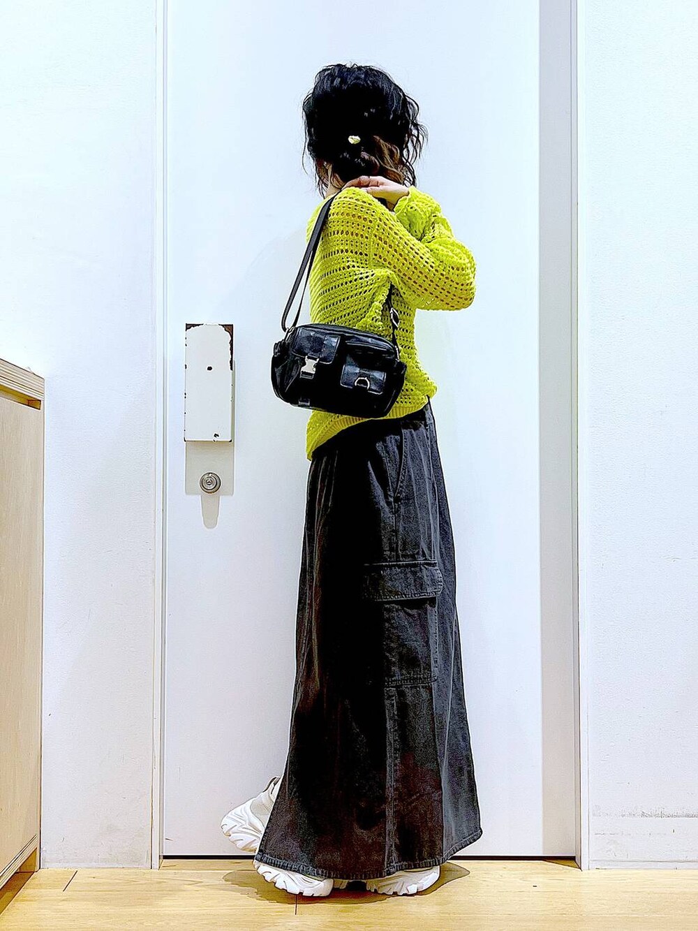 グレー系のデニムスカート、ベージュ系のスニーカー、ブラック系のショルダーバッグを着用したレディースの春コーディネートの4枚目の写真