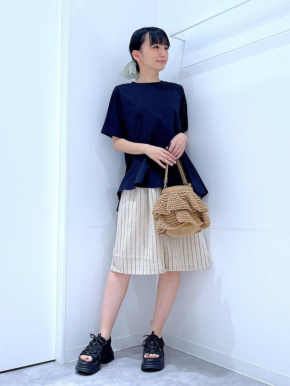 ブラック系のTシャツ/カットソー、ベージュ系のショルダーバッグ、ブラック系のサンダルを着用したレディースの夏コーディネートの2枚目の写真