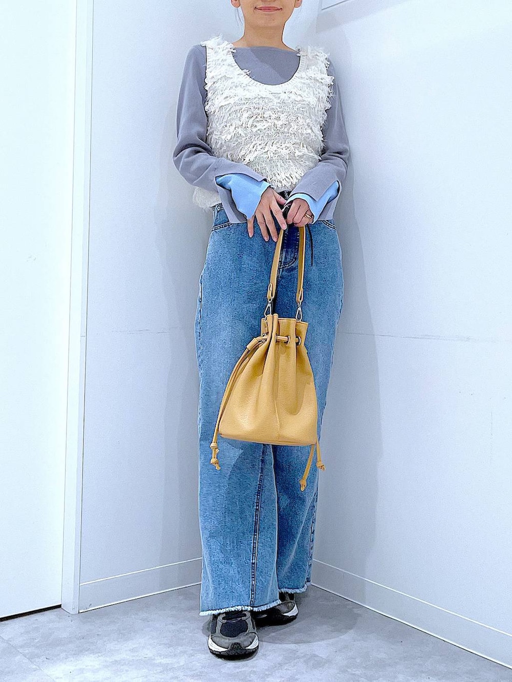 ホワイト系のベスト、グレー系のニット/セーター、ブルー系のデニムパンツを着用したレディースの春コーディネートの6枚目の写真