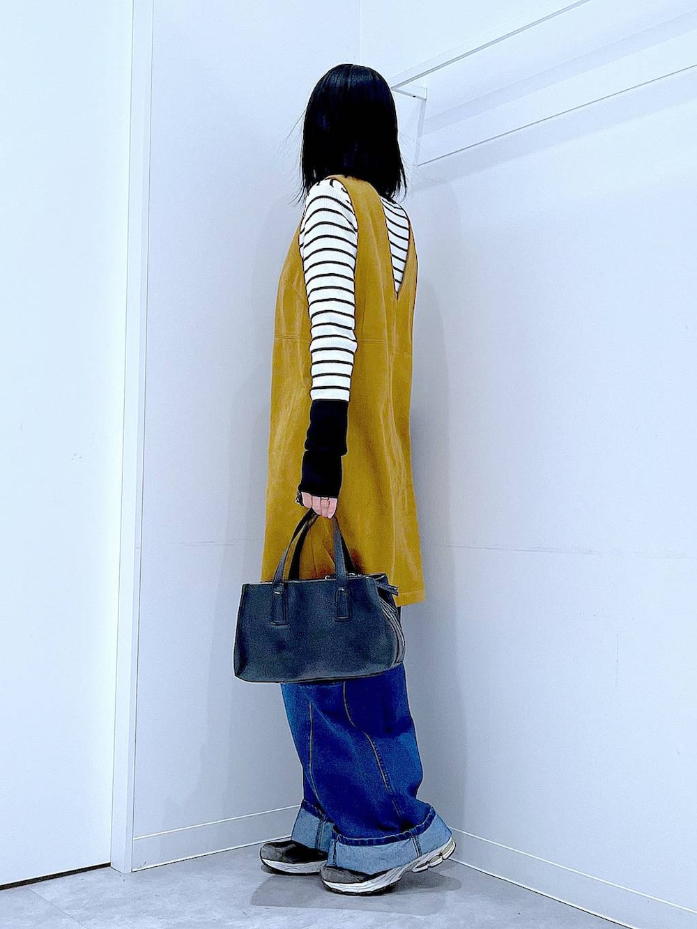 ブラック系のボストンバッグ、ホワイト系のニット/セーター、イエロー系のワンピースを着用したレディースの春コーディネートの3枚目の写真