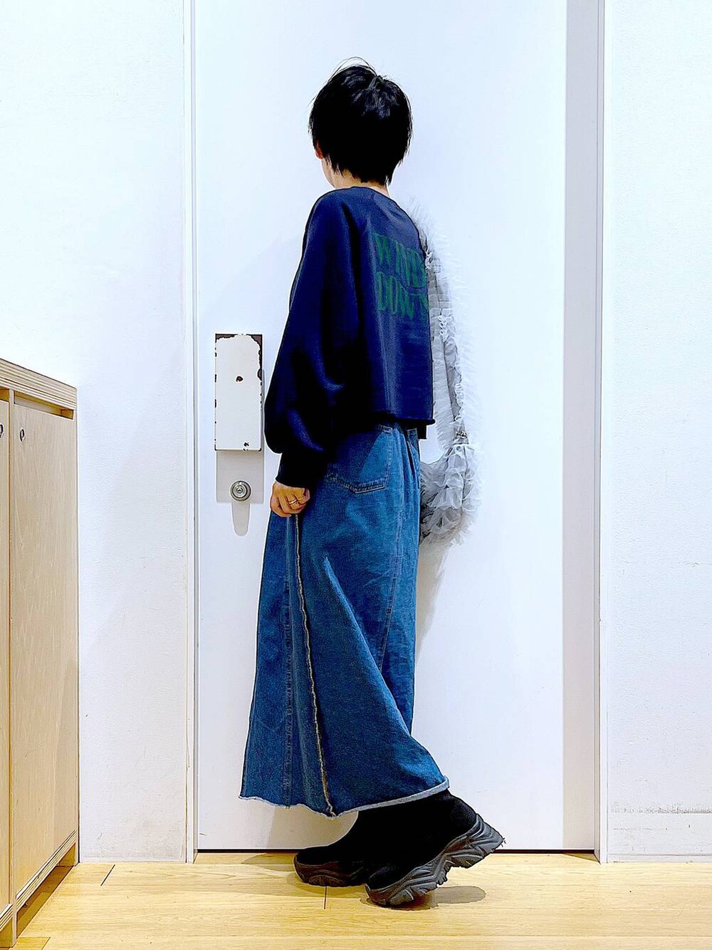 ブルー系のデニムスカート、ブラック系のブーツ、グレー系のショルダーバッグを着用したレディースの冬コーディネートの3枚目の写真