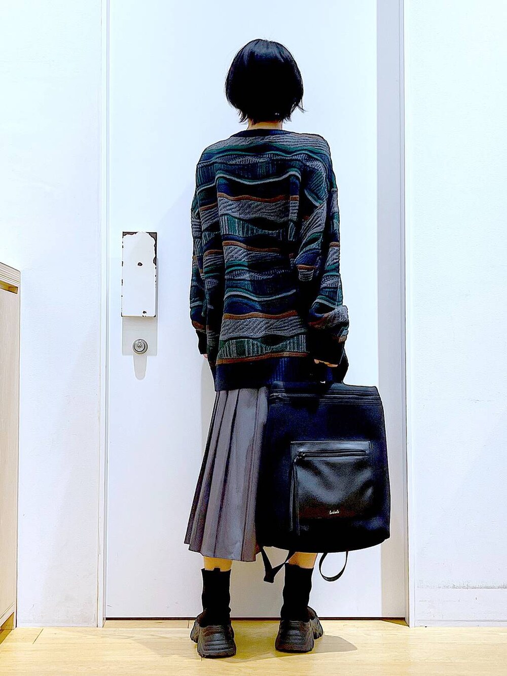 ブラック系のバックパック/リュック、ブラック系のブーツ、グレー系のスカートを着用したレディースの秋コーディネートの5枚目の写真