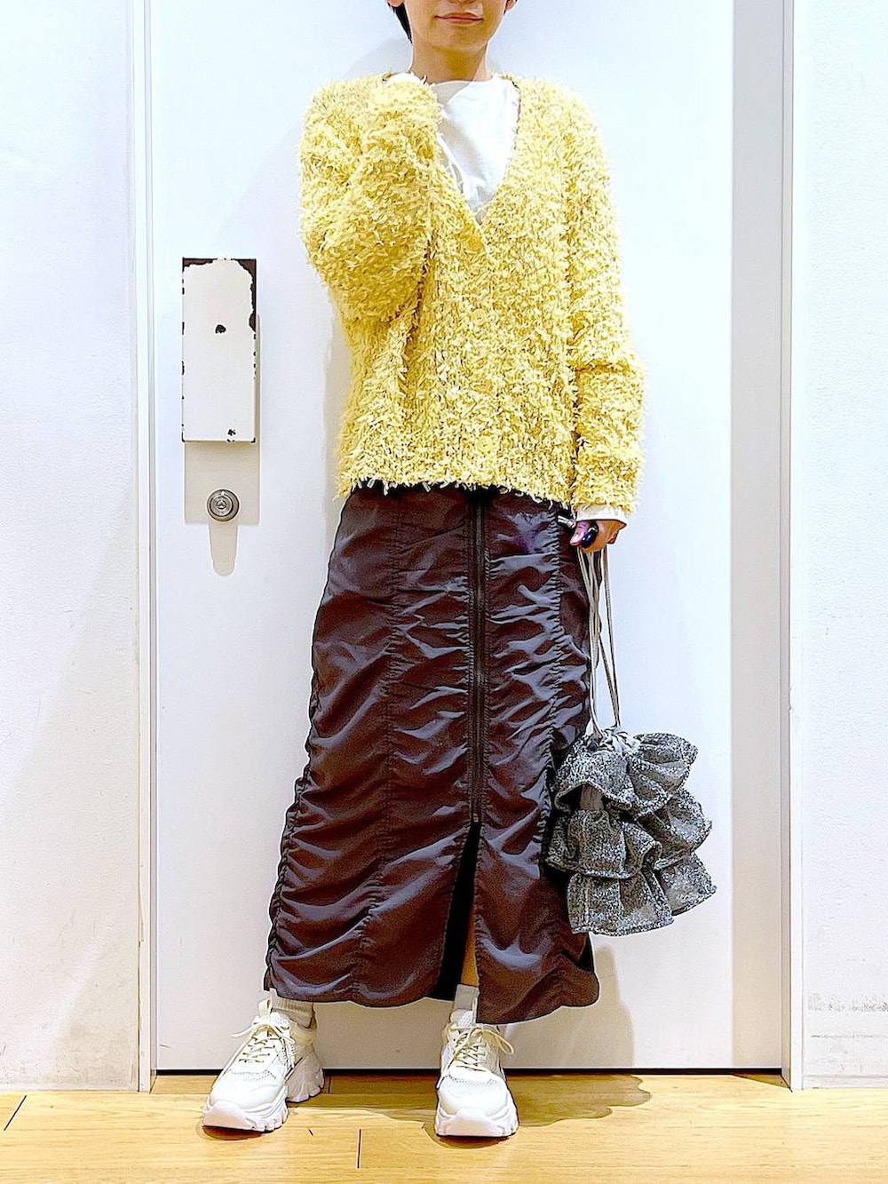 シルバー系のショルダーバッグ、グレー系のスカート、ホワイト系のスニーカーを着用したレディースの春コーディネートの6枚目の写真