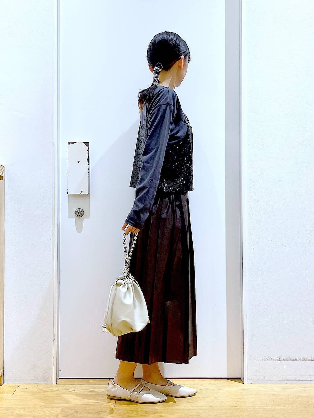 ベージュ系のショルダーバッグ、ホワイト系のパンプス、ブラック系のベストを着用したレディースの秋コーディネートの4枚目の写真