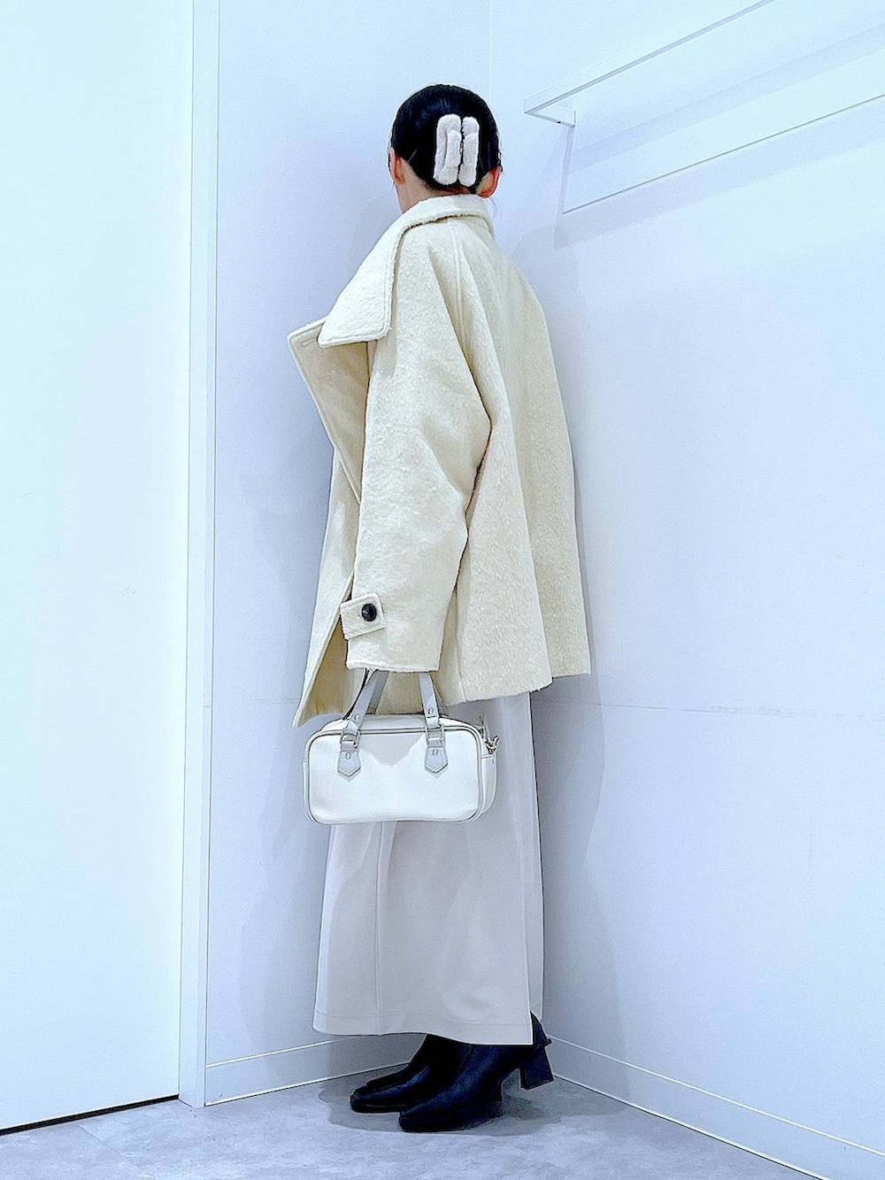 ベージュ系のスカート、ベージュ系のステンカラーコート、ブラック系のブーツを着用したレディースの冬コーディネートの3枚目の写真