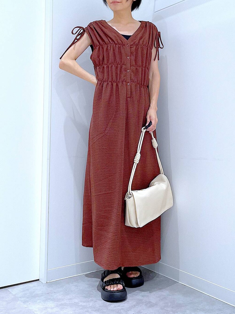 ブラック系のサンダル、ホワイト系のショルダーバッグ、ブラウン系のワンピースを着用したレディースの夏コーディネートの6枚目の写真