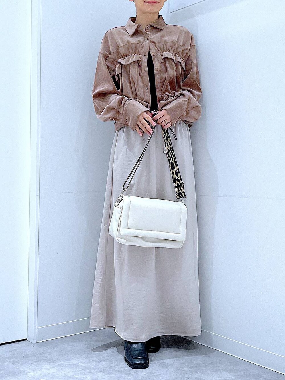 ベージュ系のスカート、ホワイト系のショルダーバッグ、ブラック系のブーツを着用したレディースの秋コーディネートの6枚目の写真