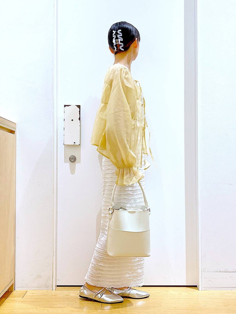 ホワイト系のベスト、ホワイト系のショルダーバッグ、ホワイト系のスカートを着用したレディースの秋コーディネートの4枚目の写真