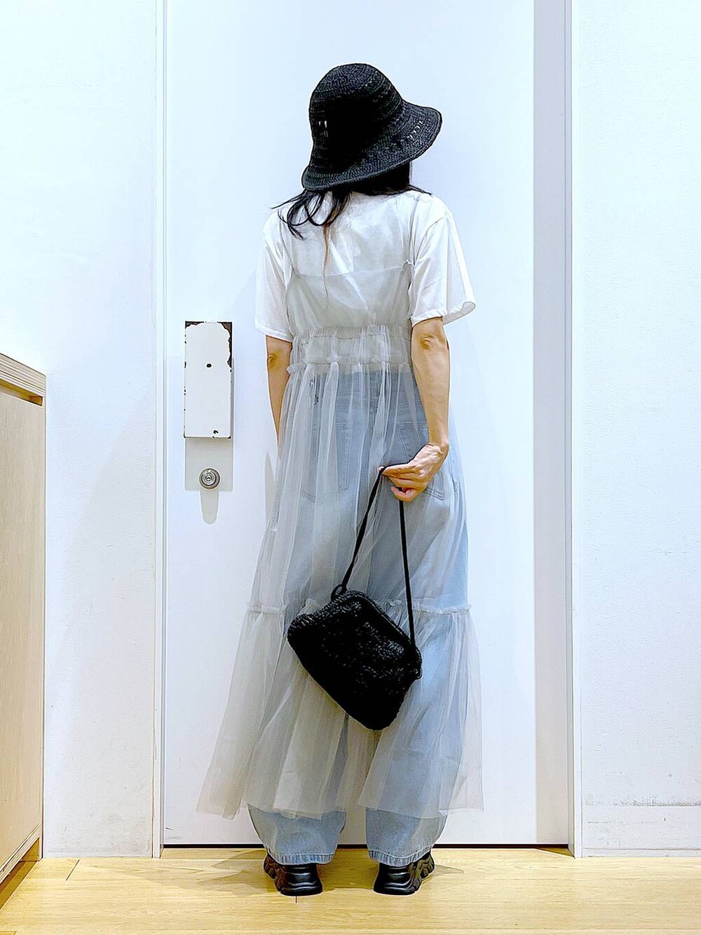 グレー系のワンピース、ブルー系のデニムパンツ、ブラック系のショルダーバッグを着用したレディースの夏コーディネートの5枚目の写真
