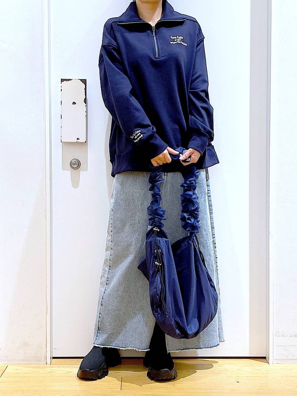 ブルー系のショルダーバッグ、ブラック系のブーツ、ブルー系のデニムスカートを着用したレディースの春コーディネートの6枚目の写真