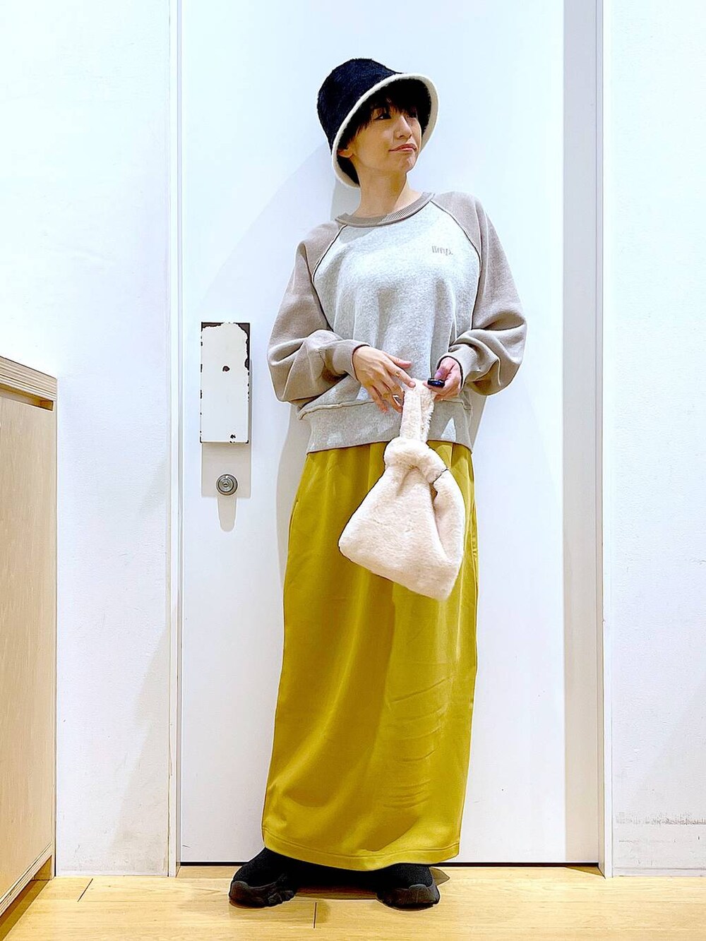 ホワイト系のショルダーバッグ、ブラック系のブーツ、ベージュ系のニット/セーターを着用したレディースの冬コーディネートの2枚目の写真