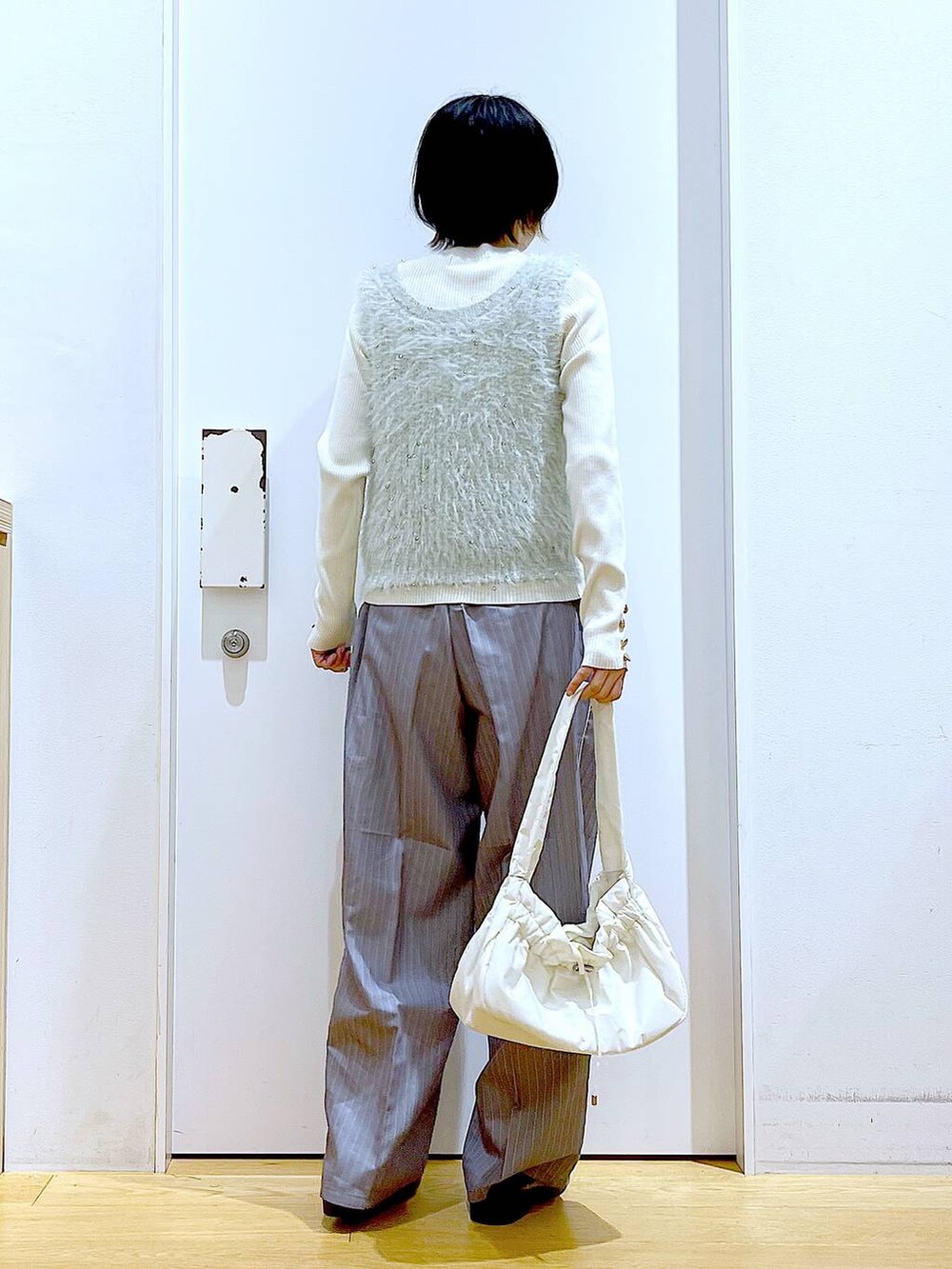 ホワイト系のニット/セーター、ホワイト系のハンドバッグ、グレー系のスラックスを着用したレディースの秋コーディネートの5枚目の写真
