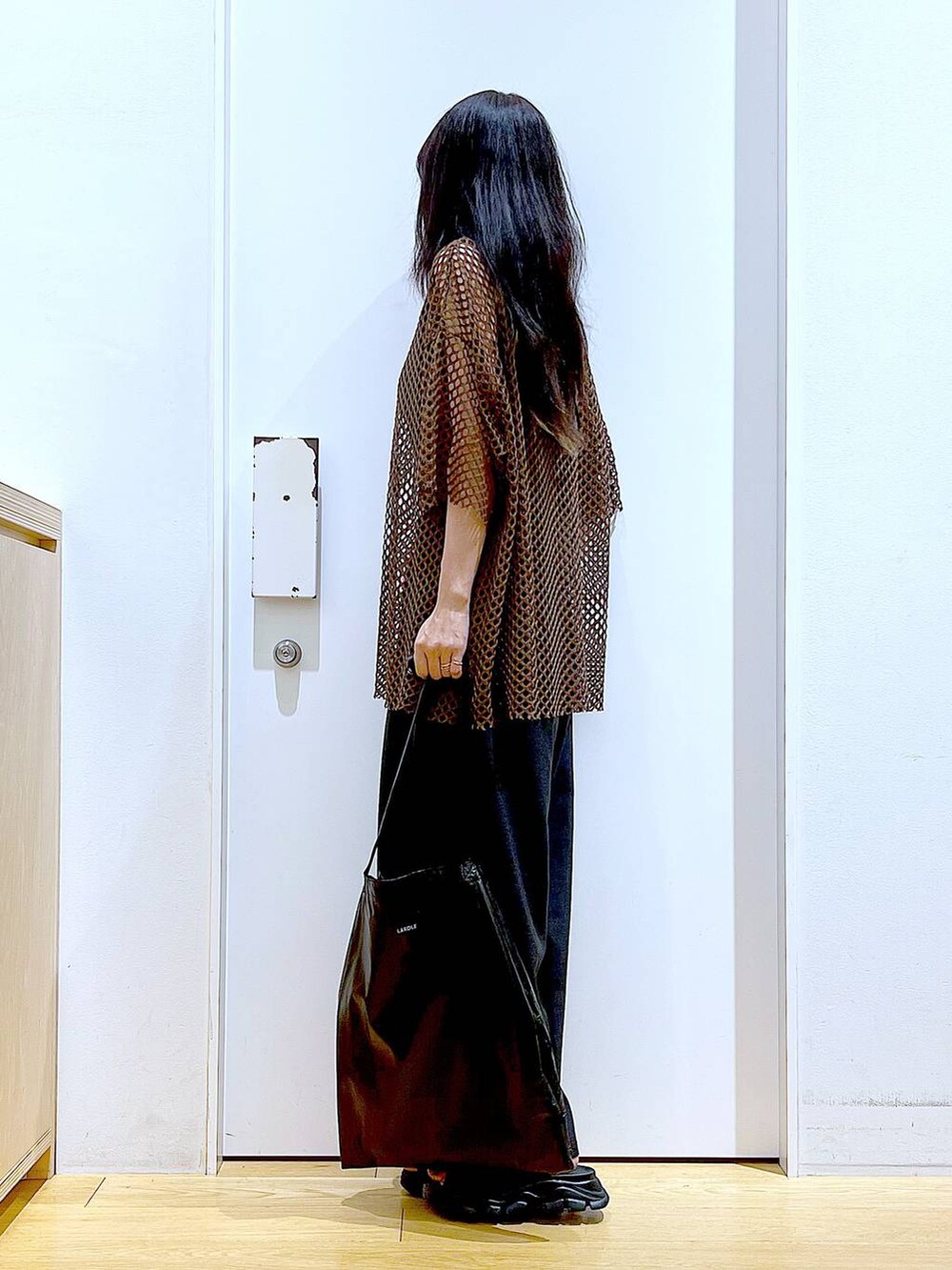 ブラック系のトートバッグ、ブラック系のニット/セーター、ブラック系のサンダルを着用したレディースの夏コーディネートの3枚目の写真