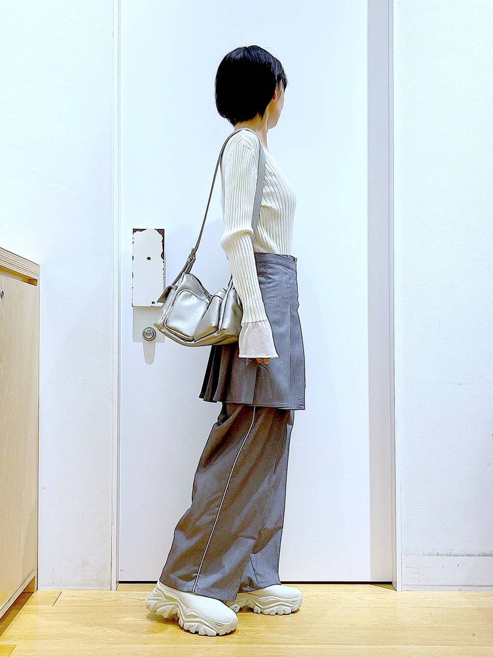 ホワイト系のニット/セーター、グレー系のスラックス、グレー系のスカートを着用したレディースの秋コーディネートの4枚目の写真