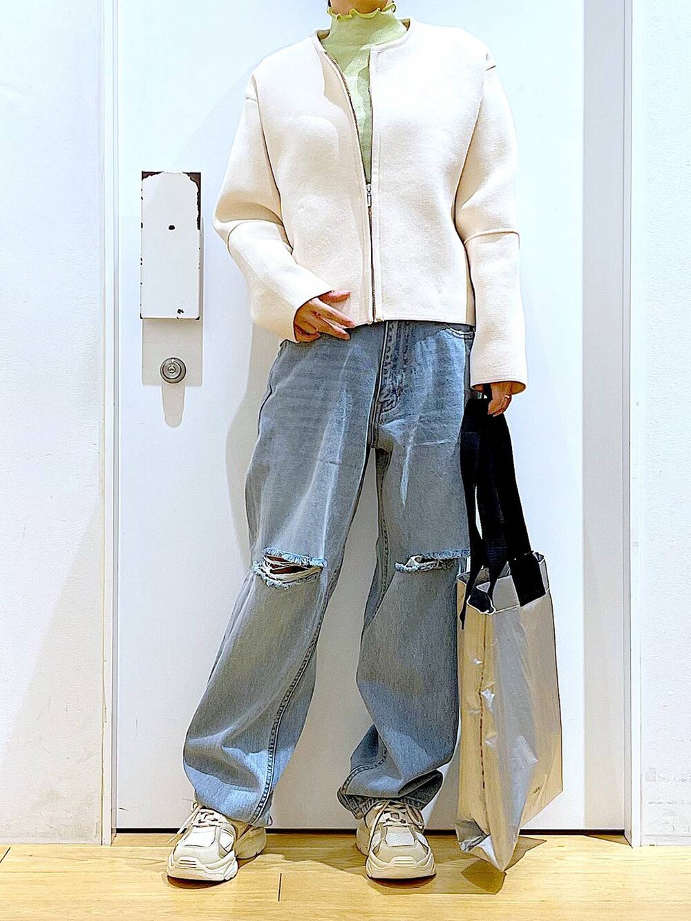 グリーン系のTシャツ/カットソー、ベージュ系のスニーカー、ブルー系のデニムパンツを着用したレディースの冬コーディネートの6枚目の写真