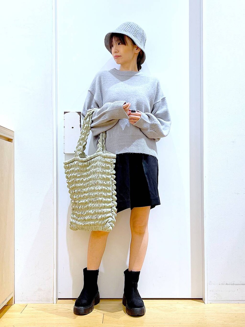 グリーン系のトートバッグ、ブラック系のブーツ、ブラック系のその他パンツを着用したレディースの冬コーディネートの2枚目の写真