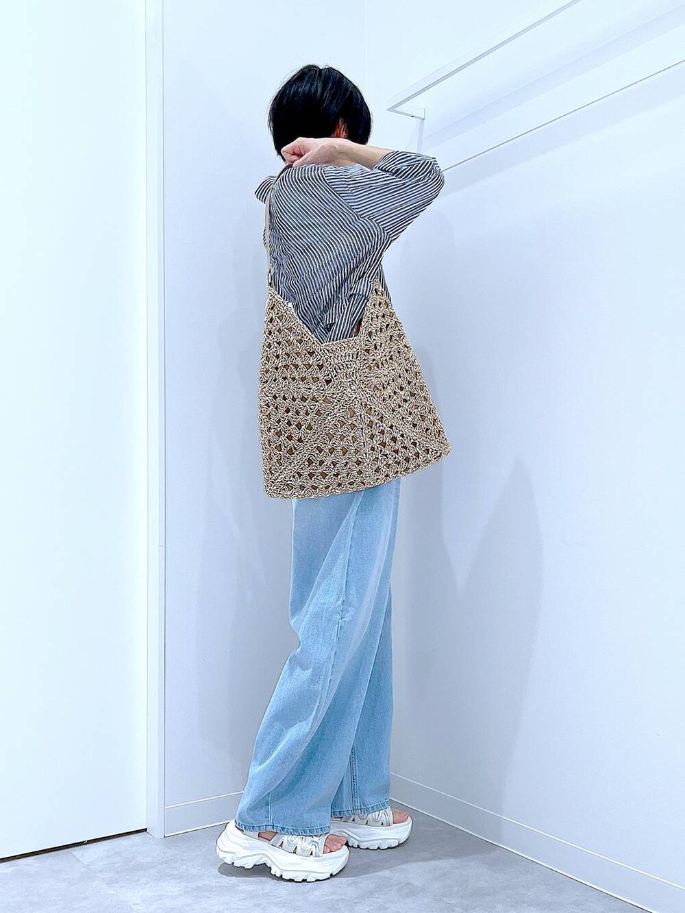 ブルー系のデニムパンツ、ベージュ系のトートバッグ、ホワイト系のスニーカーを着用したレディースの夏コーディネートの5枚目の写真