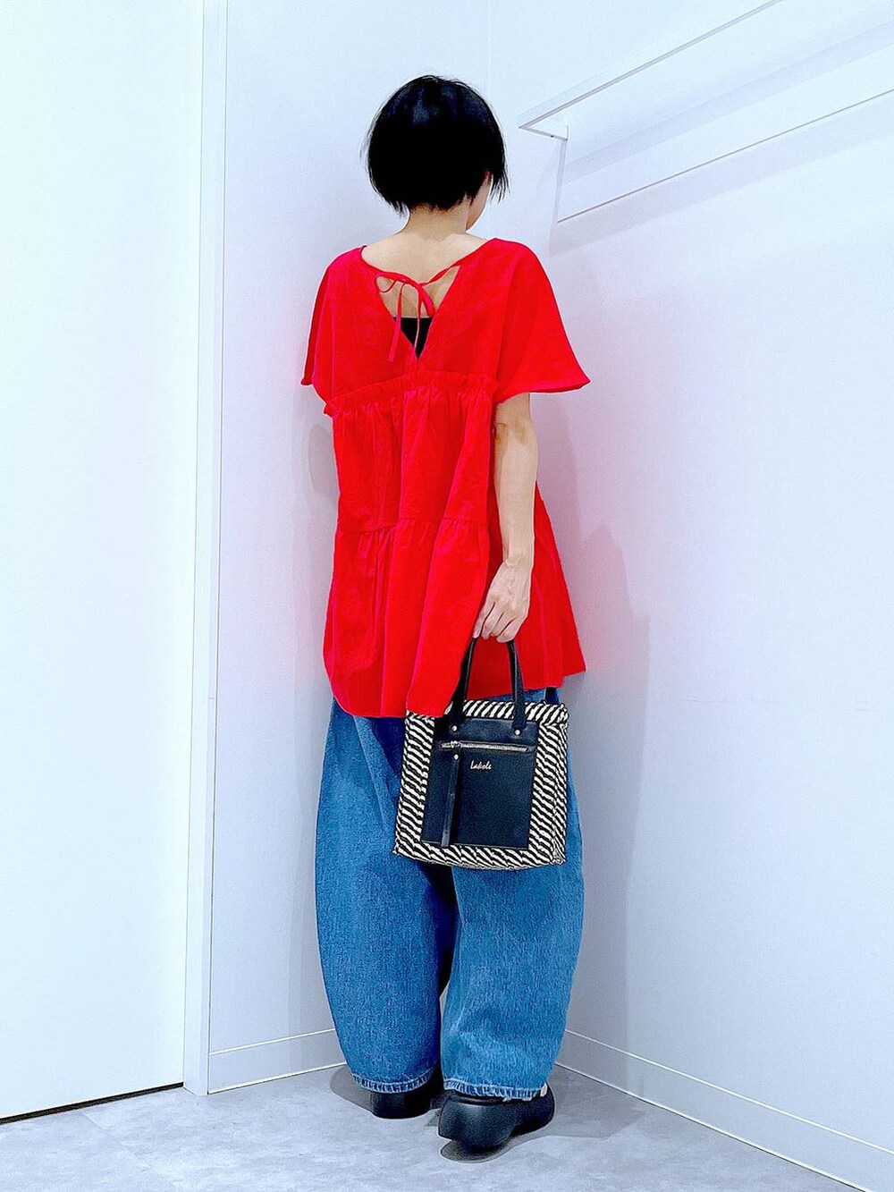 ブルー系のデニムパンツ、ブラック系のショルダーバッグ、シルバー系のサンダルを着用したレディースの夏コーディネートの5枚目の写真