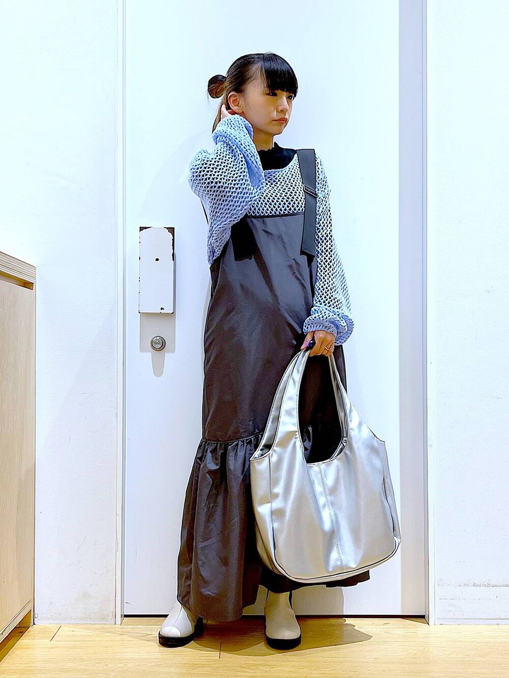 ブラック系のTシャツ/カットソー、ブルー系のニット/セーター、シルバー系のトートバッグを着用したレディースの春コーディネートの2枚目の写真