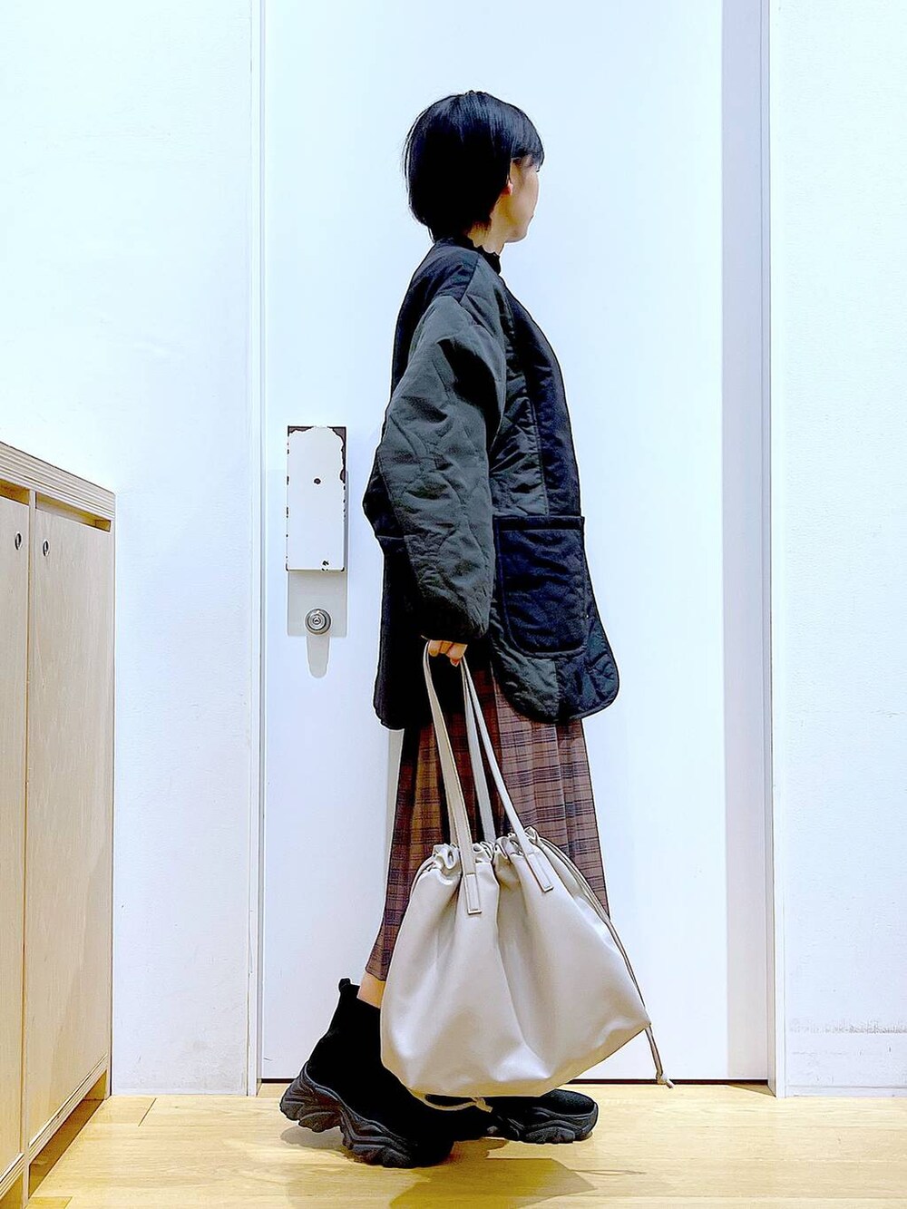 ベージュ系のトートバッグ、ブラック系のブルゾン、ブラック系のTシャツ/カットソーを着用したレディースの秋コーディネートの4枚目の写真