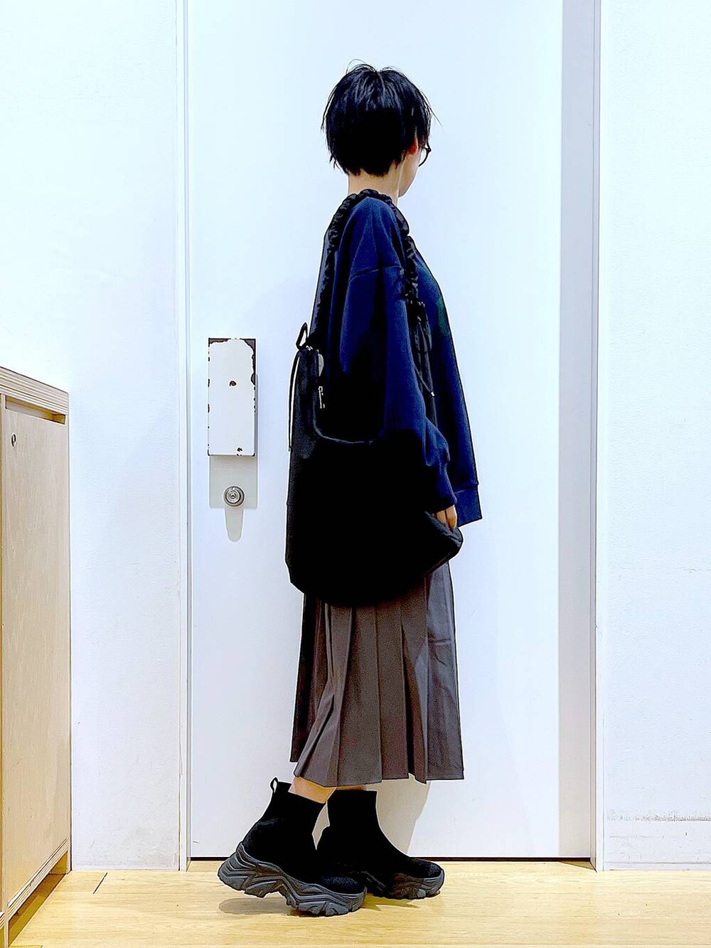 ブラック系のショルダーバッグ、ブラック系のブーツ、グレー系のスカートを着用したレディースの冬コーディネートの4枚目の写真