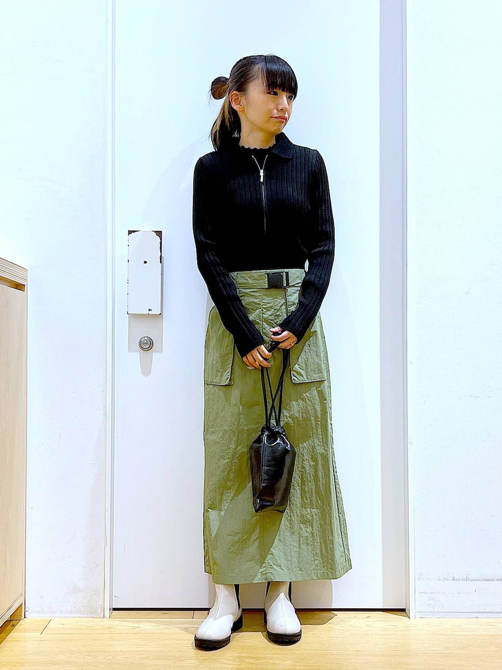 ブラック系のカーディガン/ボレロ、ベージュ系のブーツ、ブラック系のショルダーバッグを着用したレディースの春コーディネートの2枚目の写真